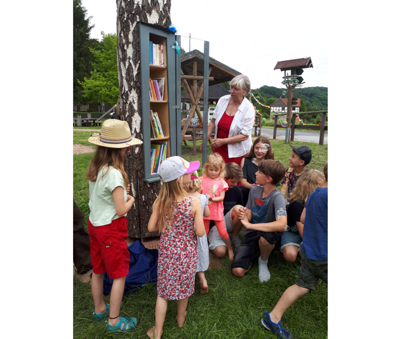 Kindern umringen den ersten Bücherbaum des Fördervereins Stadtbibliothek Eisenach e.V. auf dem Rennsteig-Spielplatz in Hörschel.