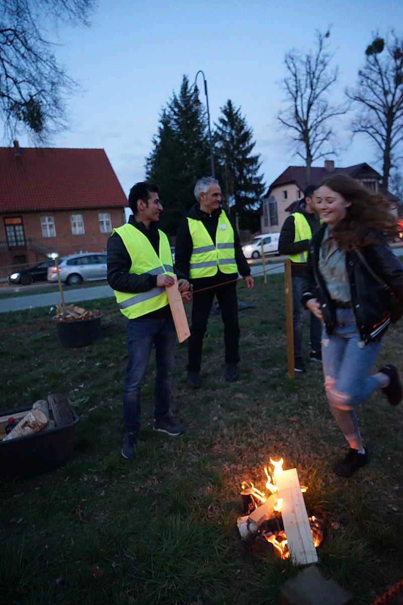 Menschen springen über kleine Feuerstellen und essen gemeinsam
