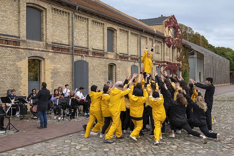 Schüler*inne mit dem Orchester während der Aufführung