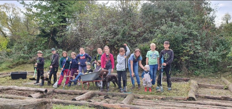 Kinder mit Gartengeräten stehen am Barfußpfad