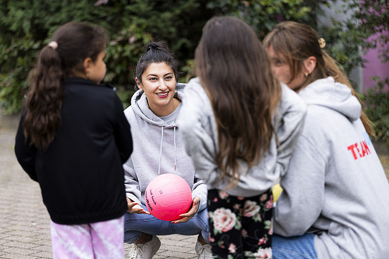 Zwei Erwachsene erklären Kindern ein Spiel