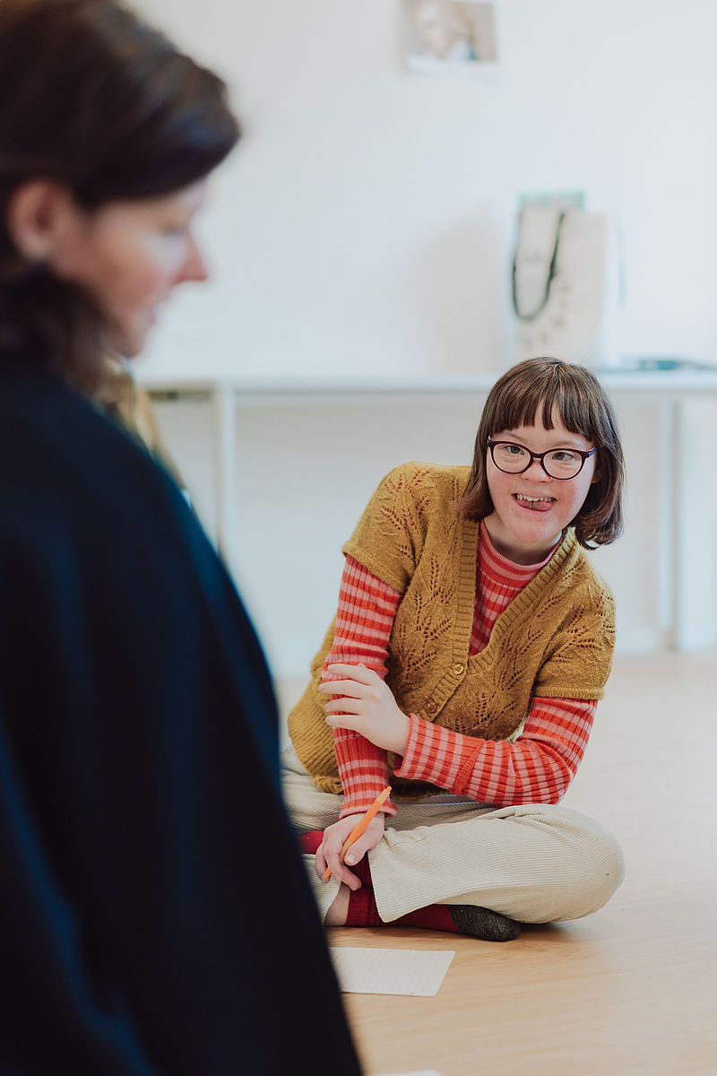 Eine Schülerin sitzt begeistert beim Sprechunterricht der Schauspielausbildung
