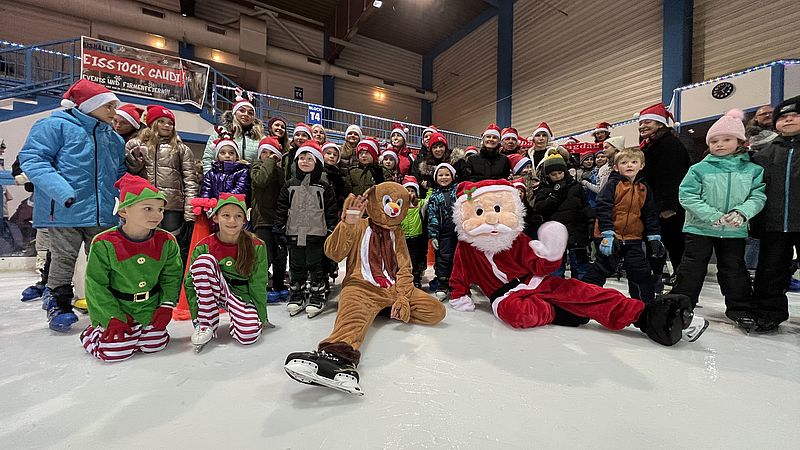 Kinder und Erwachsene mit Zipfelmützen in der Eishalle