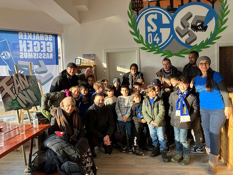 Eine Gruppe von Kindern und Erwachsenen schauen in die Kamera