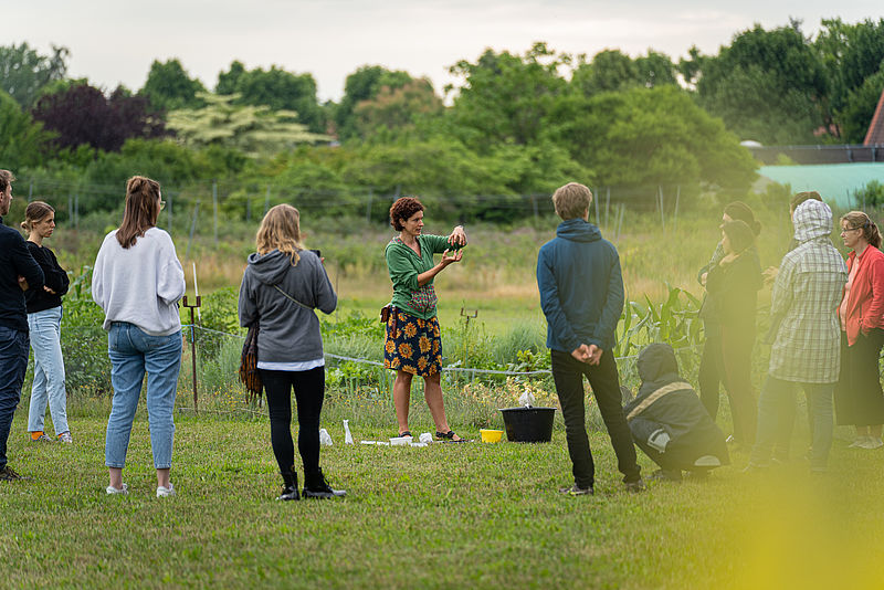 Studierende stehen im Kreis auf dem Acker