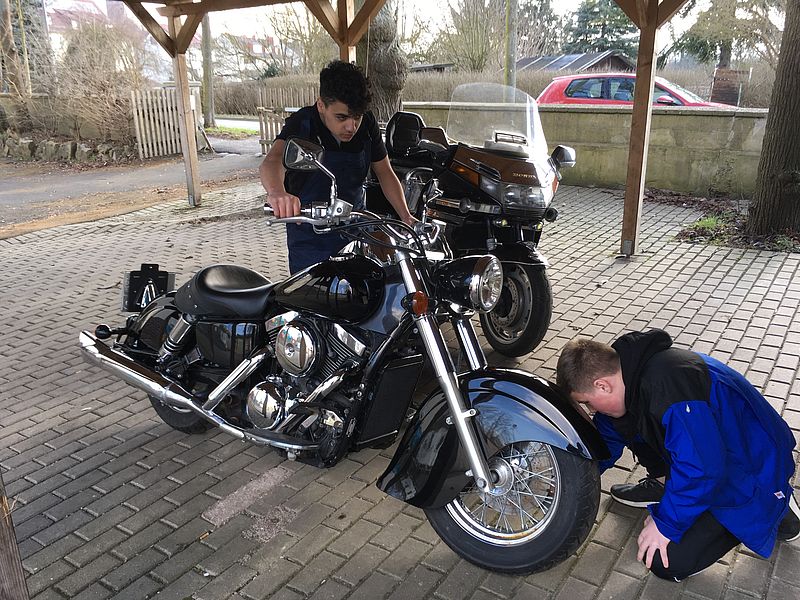 Jugendliche polieren ein Motorrad vor dem Verkauf