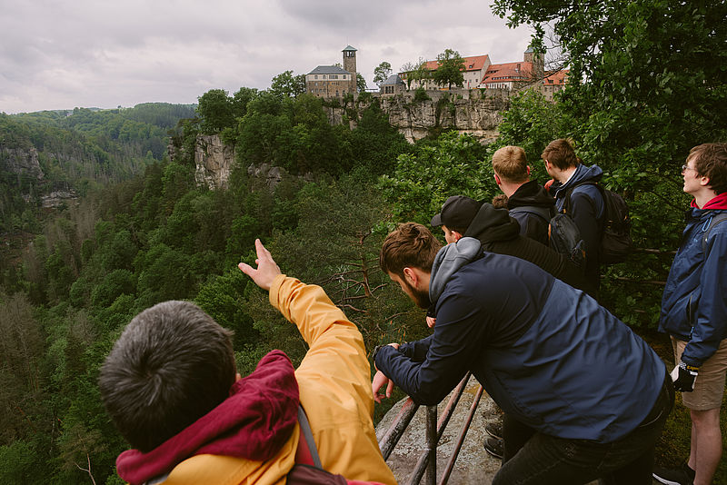 Menschen auf Aussichtspunkt auf die Burg Hohnstein