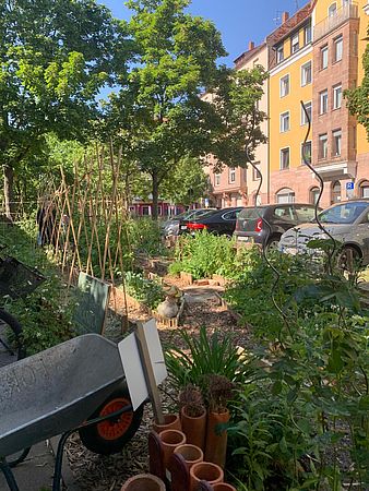 Eine Schubkarre steht vor einer kleinen zum Garten umgestalteten Grünfläche