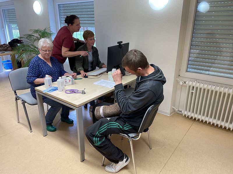 Eine Ärztin und zwei Krankenschwestern mit einem Nicht-Krankenversicherten