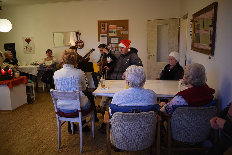 Senioren und Seniorinnen lauschen zwei Gitarrenspielern