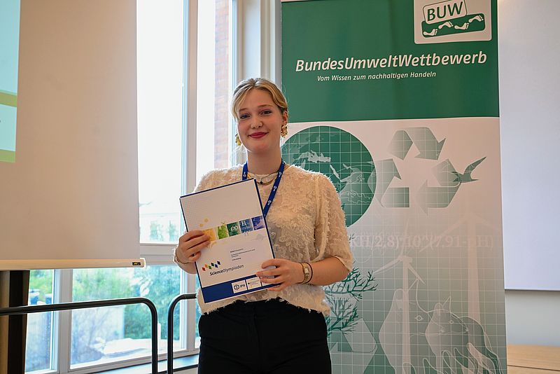 Emilie Meteling mit Urkunde vor Plakat