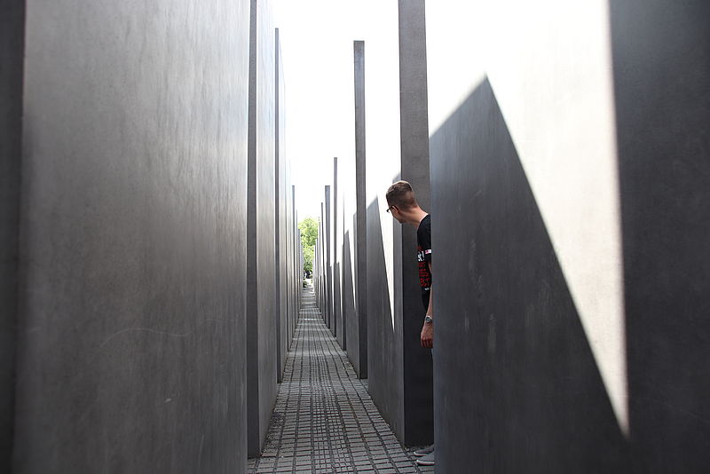 Ein Teilnehmer schaut um einen Betonblock in Richtung eines langen Ganges beim Denkmal für die ermordeten Juden Europas in Berlin. 