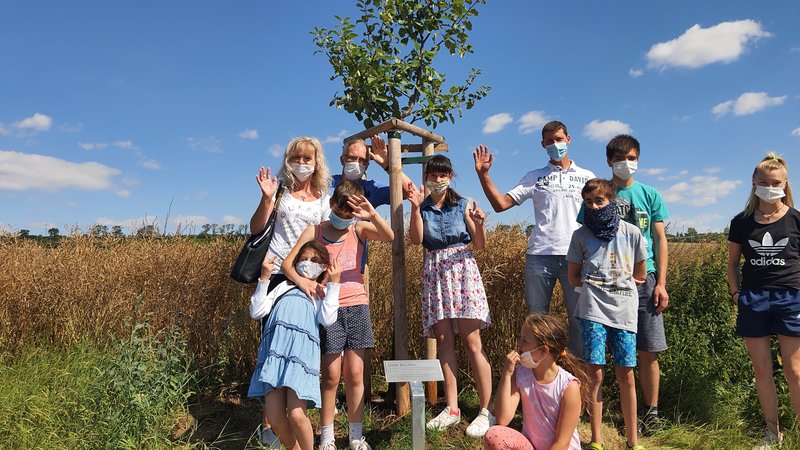 Um einen neugepflanzten Baum im Projekt 1000 winken Kinder und Jugendliche in die Kamera
