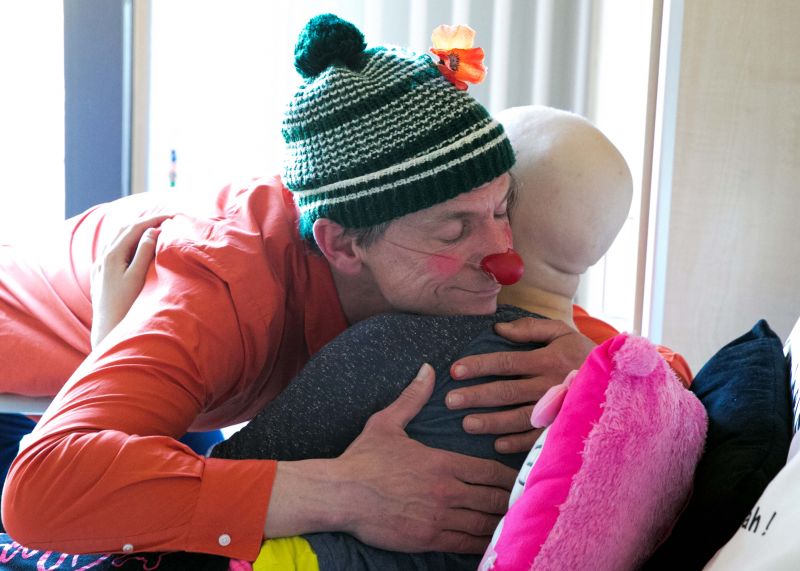 Clowns streckt Zunge raus, Kind lächelt