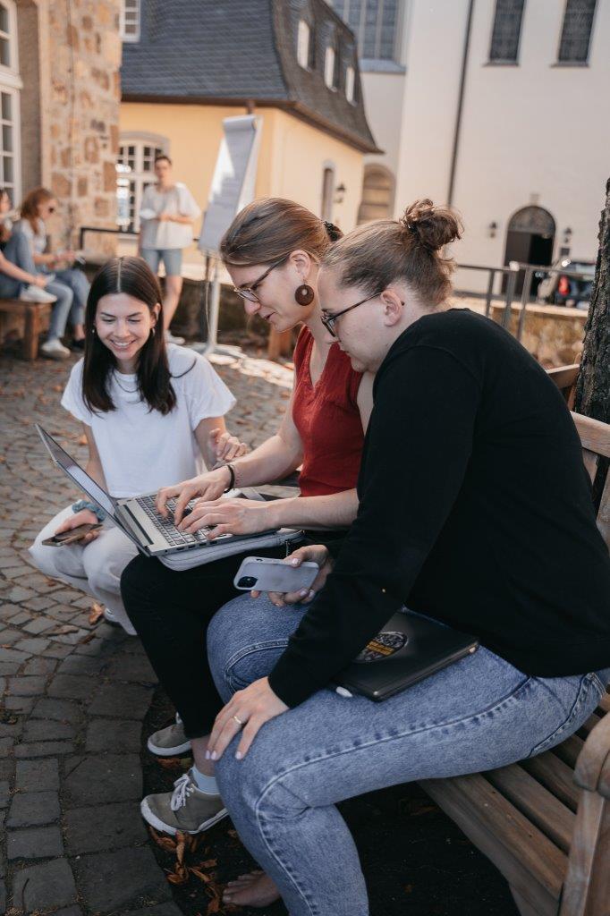 drei junge Frauen beraten sich mit Tablet und Handy